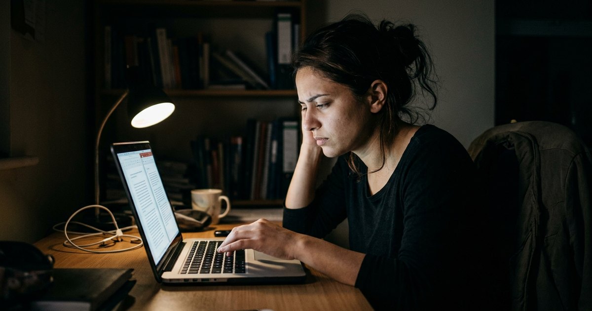 A tired doctoral student rereads a line on her screen in a dark room lit only by the monitor.
